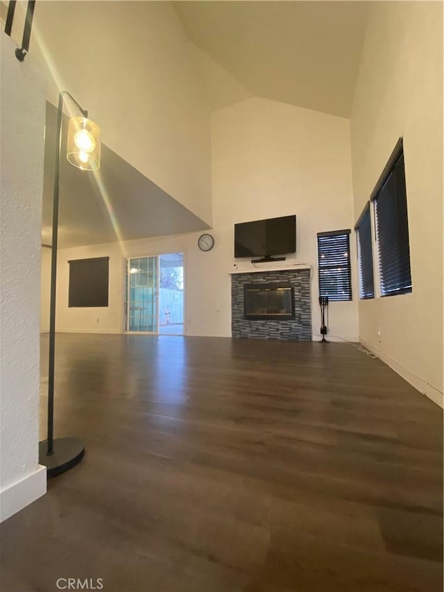 unfurnished living room featuring a stone fireplace, dark hardwood / wood-style flooring, and high vaulted ceiling