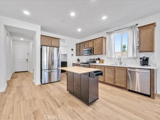 kitchen with light hardwood / wood-style floors, sink, appliances with stainless steel finishes, and a kitchen island