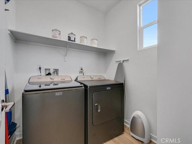 clothes washing area with light hardwood / wood-style floors and washer and clothes dryer