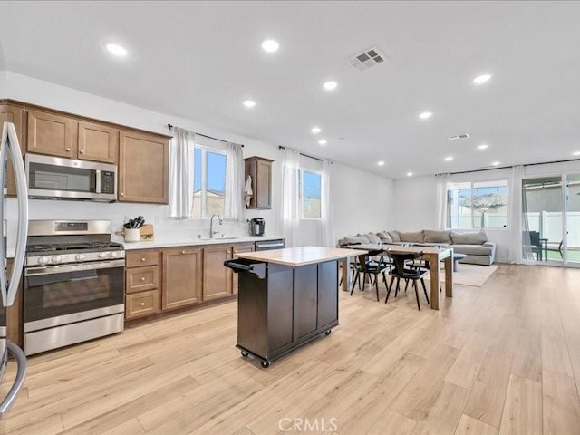 kitchen featuring a center island, appliances with stainless steel finishes, sink, and light hardwood / wood-style floors