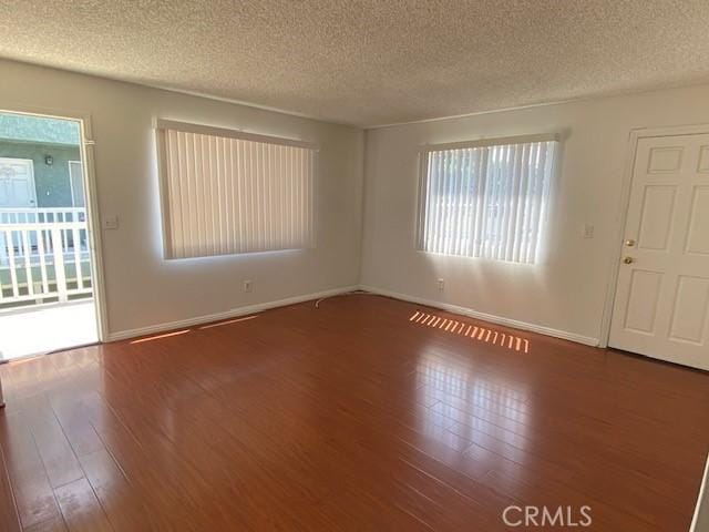 unfurnished room featuring dark wood-type flooring and a textured ceiling