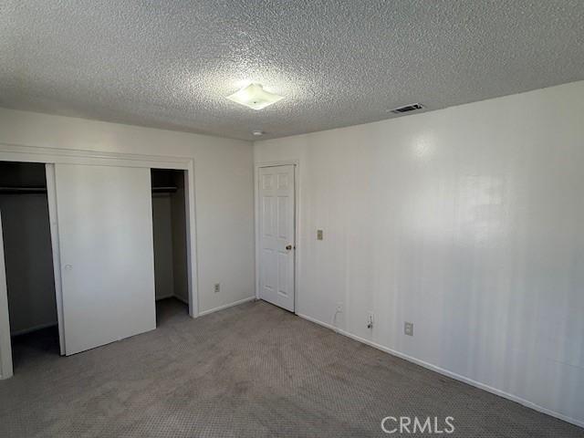 unfurnished bedroom with a closet, a textured ceiling, and carpet flooring