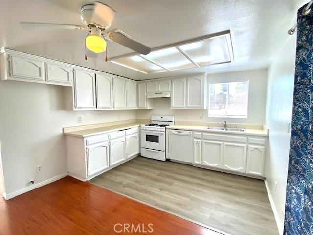 kitchen with ceiling fan, sink, white appliances, hardwood / wood-style flooring, and white cabinets