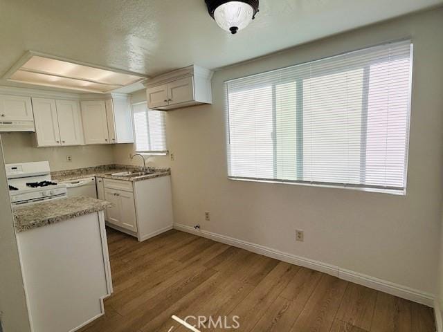 kitchen featuring light stone countertops, white appliances, white cabinets, sink, and light hardwood / wood-style flooring