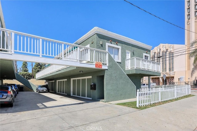 view of side of home with stucco siding, fence, and a balcony