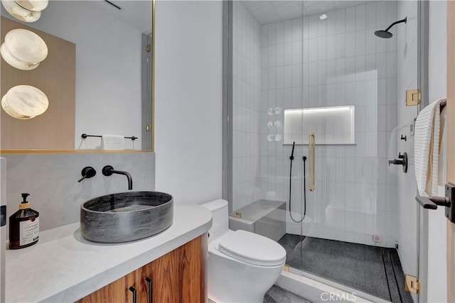 bathroom with toilet, vanity, and a shower with shower door