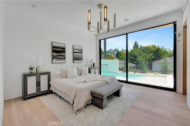 bedroom featuring a chandelier, light hardwood / wood-style floors, and access to outside