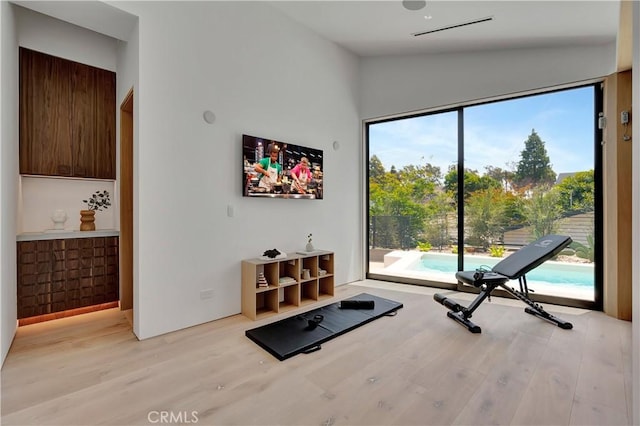 workout area with light hardwood / wood-style floors, a wealth of natural light, and vaulted ceiling