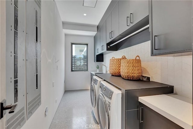 washroom with sink, washing machine and clothes dryer, and cabinets