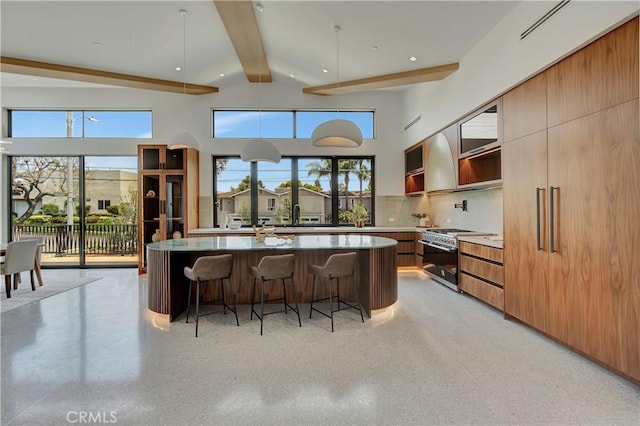 kitchen with backsplash, a kitchen island with sink, a kitchen breakfast bar, high end range, and beamed ceiling