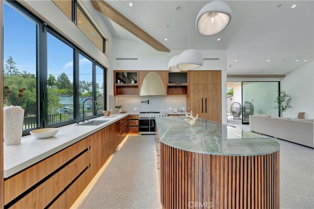 kitchen with light stone countertops, pendant lighting, tasteful backsplash, sink, and high end stove