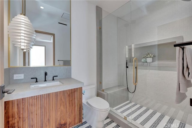 bathroom with a shower with shower door, vanity, decorative backsplash, and toilet