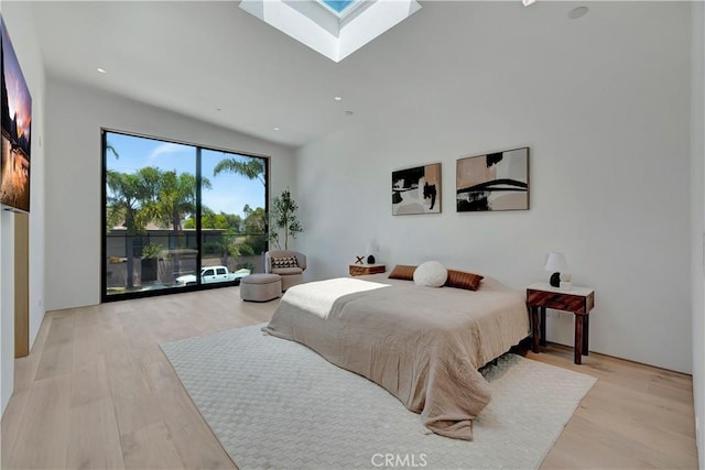 bedroom featuring a skylight, access to exterior, and light hardwood / wood-style flooring