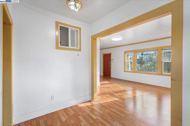 unfurnished room with light wood-type flooring and ornamental molding