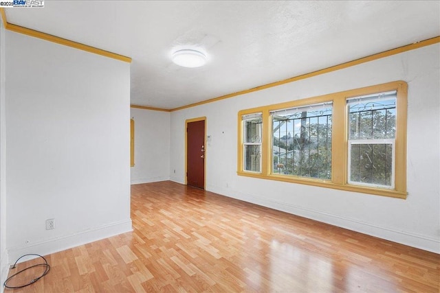 spare room with ornamental molding and light hardwood / wood-style flooring