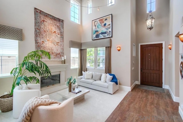 living room featuring hardwood / wood-style flooring, an inviting chandelier, a towering ceiling, and a healthy amount of sunlight