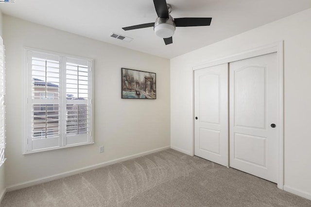 unfurnished bedroom with ceiling fan, light carpet, and a closet