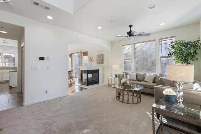 carpeted living room featuring ceiling fan and a multi sided fireplace