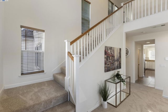 stairway with a towering ceiling and carpet