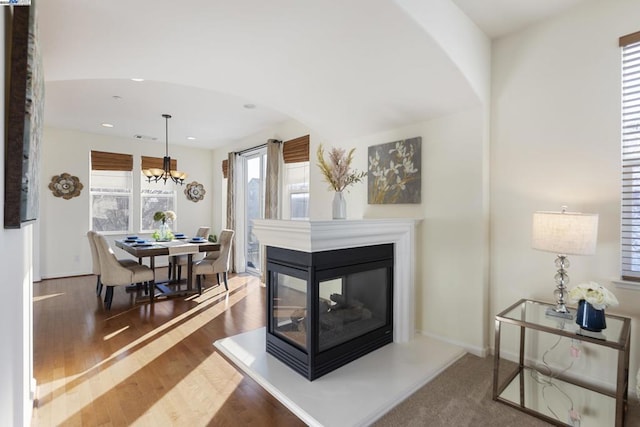 living room with an inviting chandelier, a multi sided fireplace, and hardwood / wood-style floors