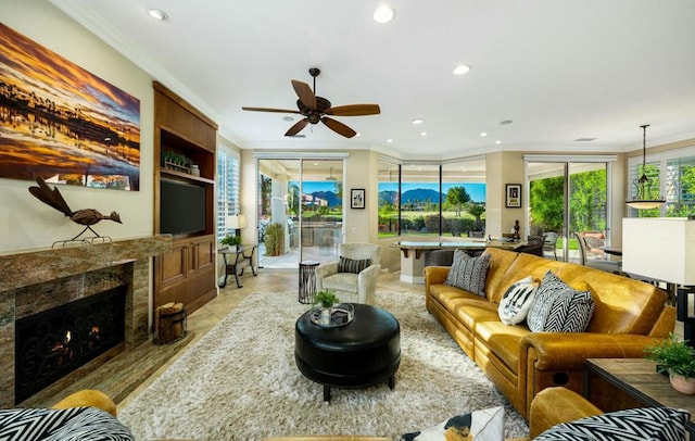 living room with ceiling fan, a high end fireplace, crown molding, and built in shelves