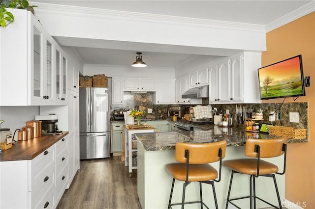 kitchen featuring white cabinetry, kitchen peninsula, stainless steel fridge, tasteful backsplash, and stove