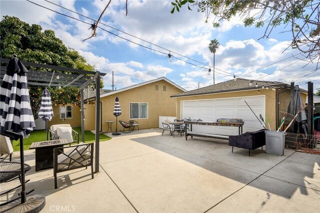 view of patio / terrace featuring fence, a fire pit, and a garage