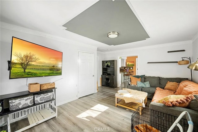 living area featuring baseboards, wood finished floors, and crown molding