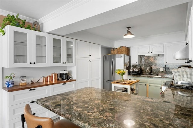 kitchen with freestanding refrigerator, a sink, decorative backsplash, ornamental molding, and wall chimney exhaust hood