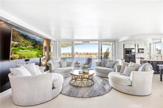 living room featuring floor to ceiling windows, light tile patterned floors, and a water view