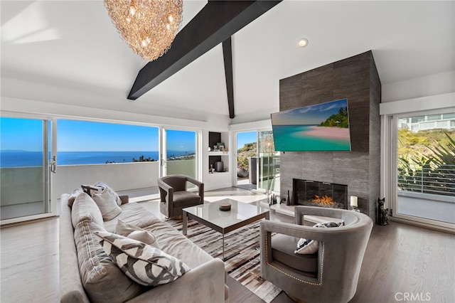 living room with vaulted ceiling with beams, an inviting chandelier, a fireplace, a water view, and hardwood / wood-style flooring