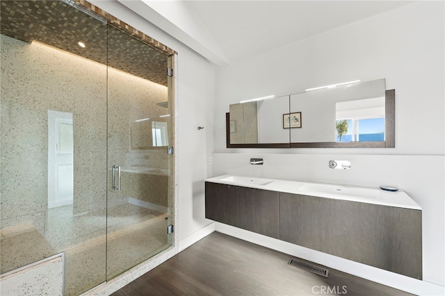 bathroom featuring hardwood / wood-style floors, walk in shower, lofted ceiling, and vanity