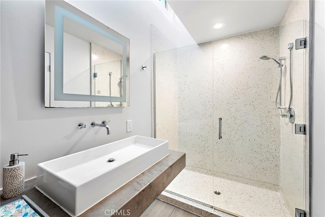 bathroom featuring a shower with shower door and sink