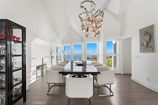 dining space with high vaulted ceiling, dark hardwood / wood-style floors, a water view, and an inviting chandelier