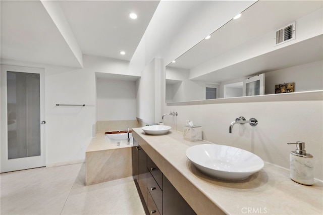 bathroom with tile patterned flooring, tiled tub, and vanity