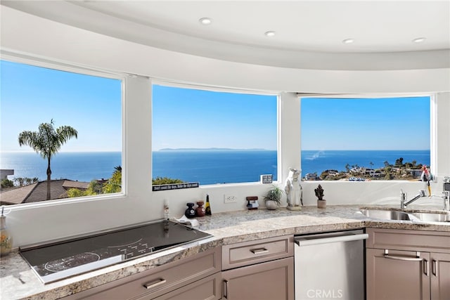 kitchen featuring a wealth of natural light, stainless steel dishwasher, black electric cooktop, and a water view