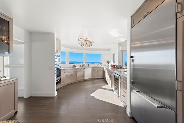 kitchen featuring appliances with stainless steel finishes, beverage cooler, dark hardwood / wood-style flooring, and a notable chandelier