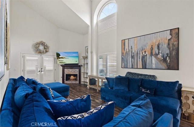 living room featuring a stone fireplace, wood-type flooring, high vaulted ceiling, and french doors