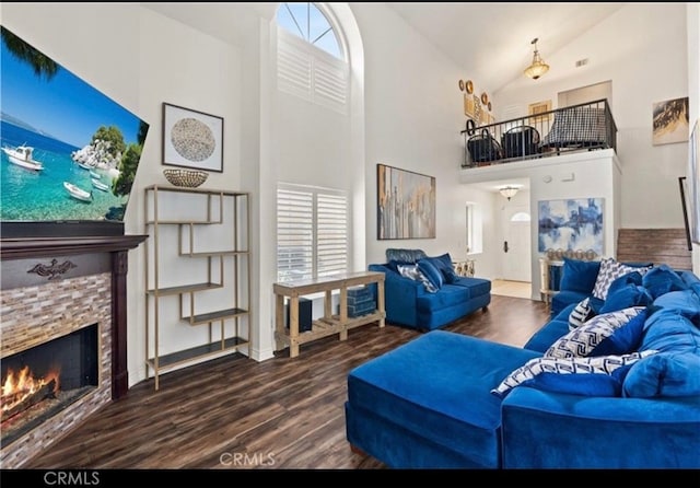 living room featuring hardwood / wood-style flooring, a stone fireplace, and high vaulted ceiling