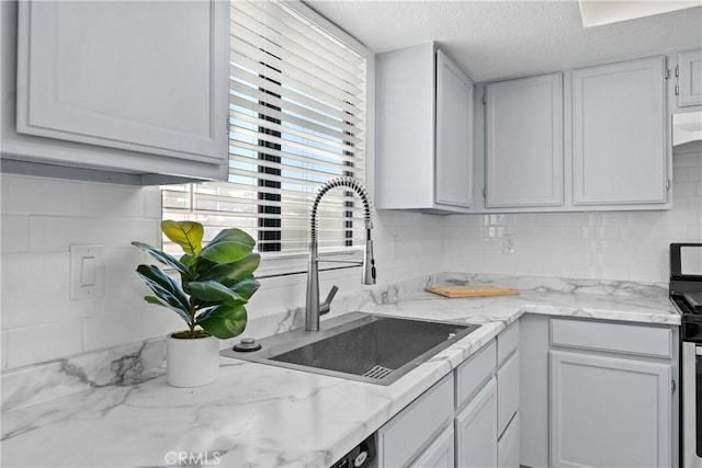 kitchen featuring decorative backsplash, sink, white cabinetry, and a textured ceiling