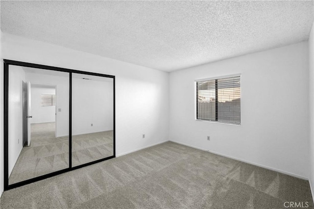 unfurnished bedroom with a textured ceiling, a closet, and light colored carpet