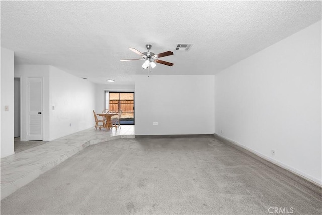 spare room with ceiling fan, light colored carpet, and a textured ceiling