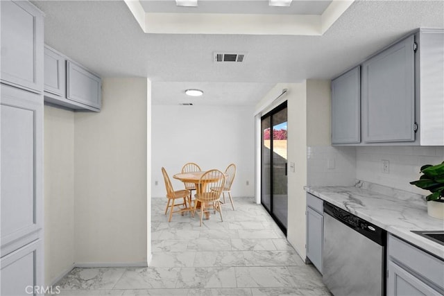 kitchen with stainless steel dishwasher, gray cabinetry, decorative backsplash, and light stone counters