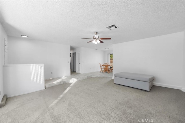 unfurnished room with ceiling fan, light colored carpet, and a textured ceiling