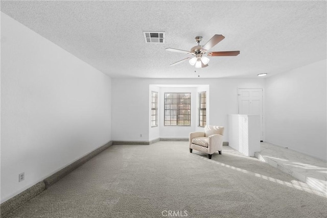 unfurnished room with light carpet, ceiling fan, and a textured ceiling