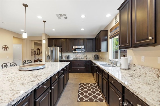 kitchen featuring stainless steel appliances, hanging light fixtures, sink, and dark brown cabinetry