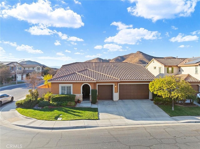 mediterranean / spanish house featuring a mountain view, a garage, and a front lawn