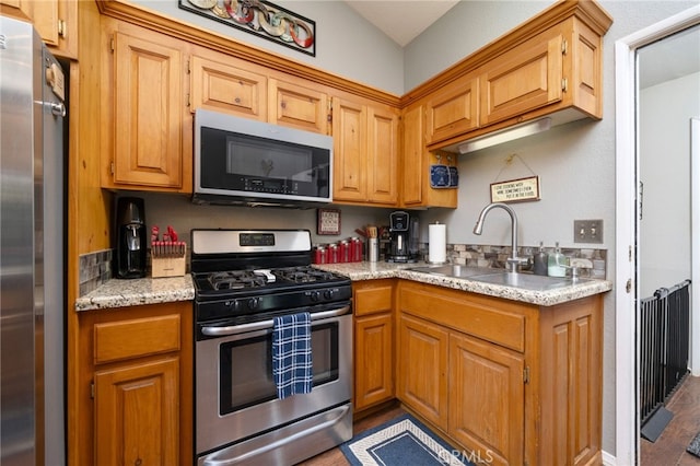 kitchen featuring light stone counters, sink, and appliances with stainless steel finishes