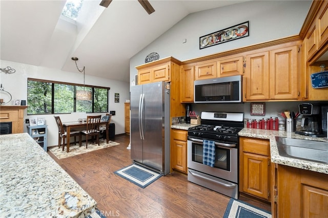 kitchen with appliances with stainless steel finishes, dark wood-type flooring, lofted ceiling with skylight, light stone counters, and sink