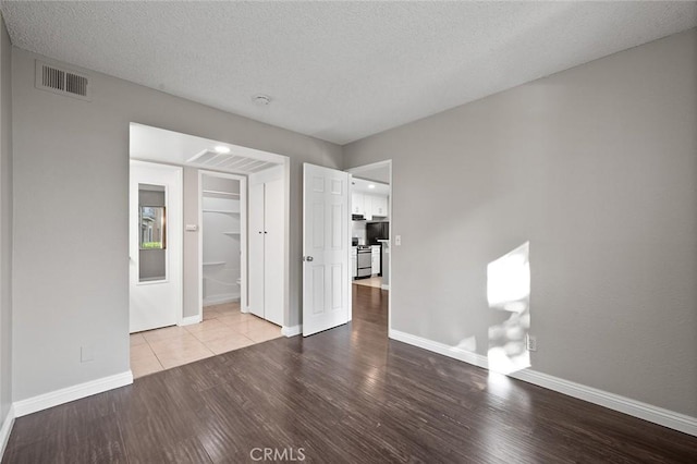 empty room with a textured ceiling and light hardwood / wood-style flooring